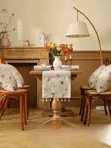 Close-up of beige linen table runner with yellow floral embroidery and fringe trim