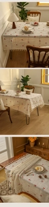 Detailed close-up of pastoral cherry embroidery and white tassel fringe on beige tablecloth