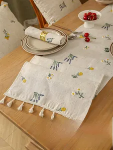 Detail of linen table runner with lavender floral embroidery and elegant white tassels