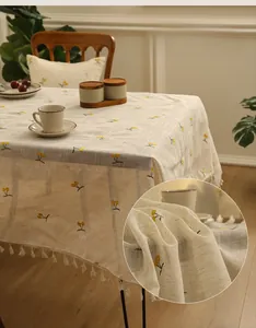 Detailed view of linen tablecloth with yellow berry embroidery and white tassel edge