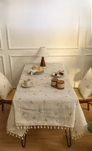 Detail of embroidered yellow cherry patterns and white fringe on linen tablecloth