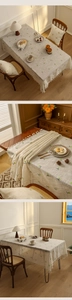 Close-up of cotton linen tablecloth featuring green cherry embroidery and tassel edge