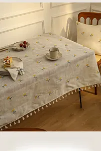 Close-up of linen tablecloth with yellow cherry embroidery and white tassel edges