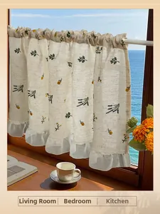 Detailed embroidery on linen cafe curtains featuring floral patterns and a sheer ruffle edge