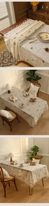 Detail of beige tablecloth with yellow pineapple embroidery and white fringe tassels