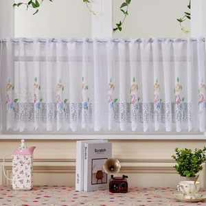 White lace cafe curtain with colorful floral embroidery in a cozy rustic kitchen setting