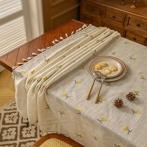 Pastoral linen tablecloth with yellow cherry embroidery and ivory tassels on wooden table