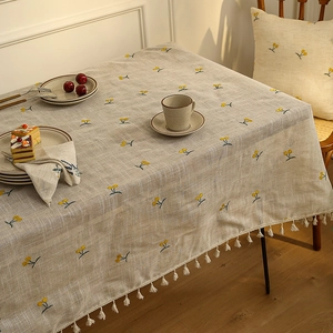 Linen table cloth with cherry embroidery and white tassel fringe in a cozy setting