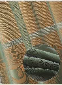 Close-up of dark green lace curtain fabric with delicate floral patterns and mesh texture