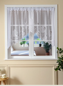 Detail of white lace cafe curtain featuring intricate teapot and floral woven patterns