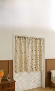 Close-up of beige cotton linen curtain with floral patterns and delicate tassel trim