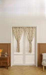 Detail of linen door curtain with wheat embroidery, tassel edges and rope tieback