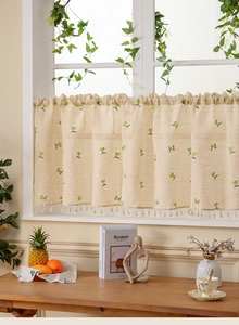 Detail view of linen coffee curtain with green embroidery and beige tassel trim