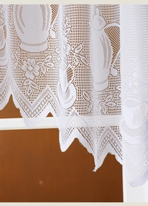 Detail of white French lace curtain with floral patterns and scalloped edge finish