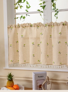 Close-up of linen cafe curtain featuring green berry embroidery and elegant fringe trim