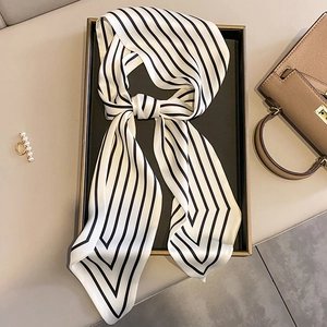 Elegant black and white striped skinny silk scarf tied in a knot on a luxury display tray