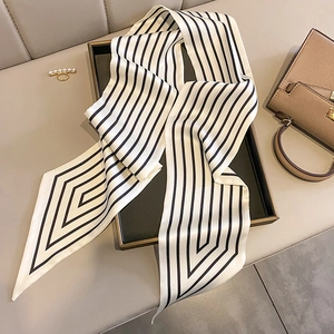 Close-up of black and white striped skinny silk scarf on a tray with a pearl ring