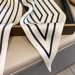 Detailed view of striped satin scarf with geometric diamond patterns in a gift box