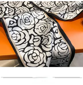 Dettaglio foulard in seta camelia con rose nere e bianche su elegante confezione regalo arancio