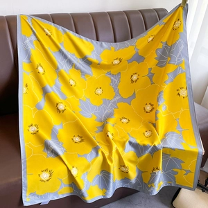Detail of yellow floral silk scarf draped on a sofa showing glossy texture and drape