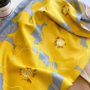 Detailed macro view of yellow and blue floral silk scarf with elegant satin texture