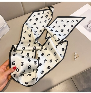Détail d'un foulard twilly beige en soie avec imprimés de chiffres noirs et liseré