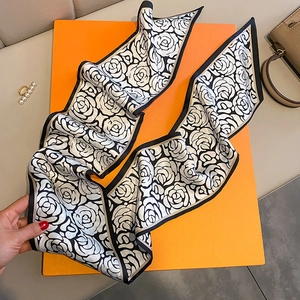 Dettaglio foulard in seta con rose nere posato su una scatola regalo arancio
