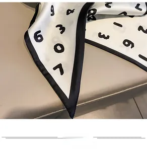 Détails macro du foulard en soie ivoire avec chiffres noirs et texture satinée et soyeuse