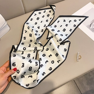 Détail d'un foulard étroit en satin blanc avec imprimé numérique noir et bordure sombre
