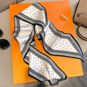 Dettaglio di un elegante foulard in seta bianco e nero con motivo geometrico su arancione
