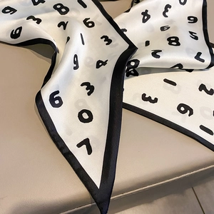 Détail d'un foulard en soie blanche avec chiffres noirs montrant la texture lisse