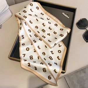 Détail d'un foulard en soie à imprimé numérique avec bordure marron sur un plateau