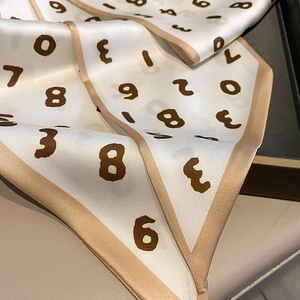 Gros plan sur foulard en soie avec motifs de chiffres bruns et bordures dorées élégantes