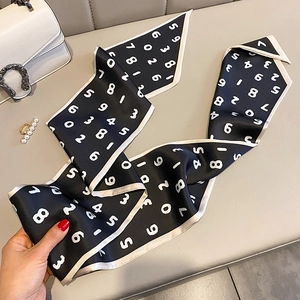Détail d'un foulard étroit en soie noire avec chiffres blancs et bordure contrastée