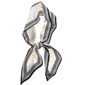 Elegante foulard in seta camelia bianca con motivo geometrico nero annodato a fiocco