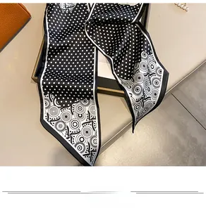 Detail of a black and white polka dot silk twilly scarf tied to a leather handbag