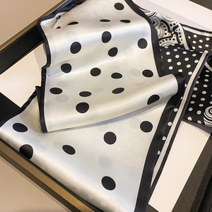 Detailed view of polka dot silk scarf with elegant pattern on display tray