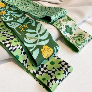Detailansicht von drei grünen Seidenschals mit Leoparden-, Blatt- und Karomustern
