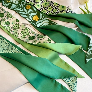 Detailansicht verschiedener grüner Seidenschals mit Blumen- und Leopardenmustern