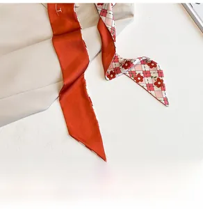 Détail d'un foulard en soie rouge à fleurs drapé sur un vêtement beige élégant