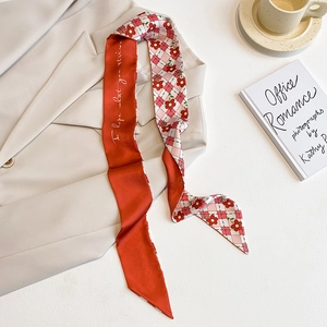 Détail d'un foulard twilly rouge à motif floral et carreaux sur un blazer beige
