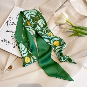 Nahaufnahme des grünen Blumen-Seidenschals auf einem beigen Blazer mit Tulpendekoration