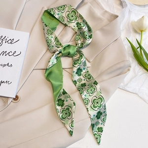 Grüner Seidenschal mit Blumenmuster als Schleife gebunden auf einem beigen Sakko