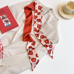 Écharpe longue en soie rouge avec imprimé marguerites sur une veste beige chic
