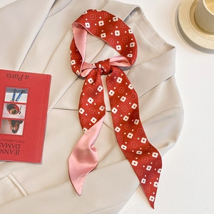 Foulard twilly en soie à fleurs rouge et rose noué en nœud sur un blazer beige