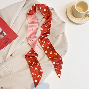 Détail d'un foulard étroit à fleurs rouge et rose drapé sur un blazer avec décor chic