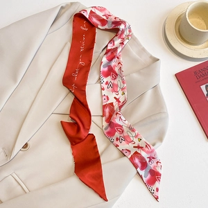 Détail d'un foulard étroit en soie imprimé cœurs rouges et blancs sur une veste