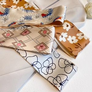 Detail of elegant silk-like skinny scarves with floral and F-logo patterns on fabric