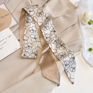 Long silk scarf with black floral print on beige suit paired with white roses
