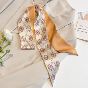 Macro detail of champagne and orange silk scarf with diamond H-pattern on beige suit